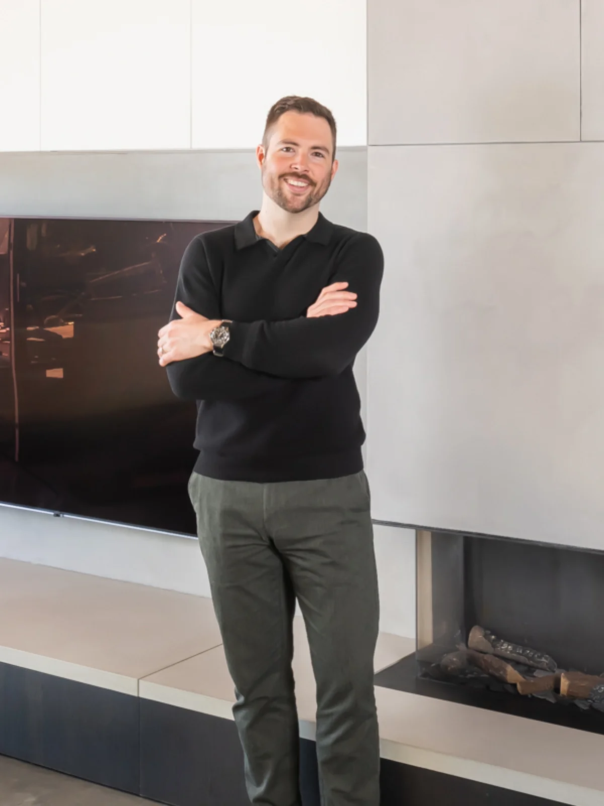 Gabe Penner, third-generation founder of Shape of Paint, standing by a modern concrete fireplace